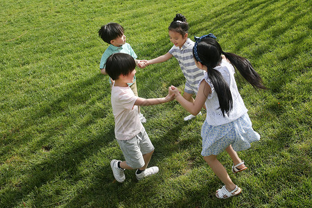 友谊可爱的四个人快乐的孩子们在草地上玩耍图片