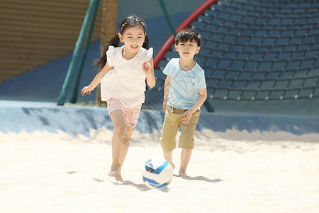 男孩跑白昼儿童在沙子里踢球图片