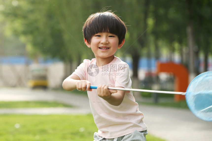 水平构图注视镜头幸福小男孩在草地上玩耍图片