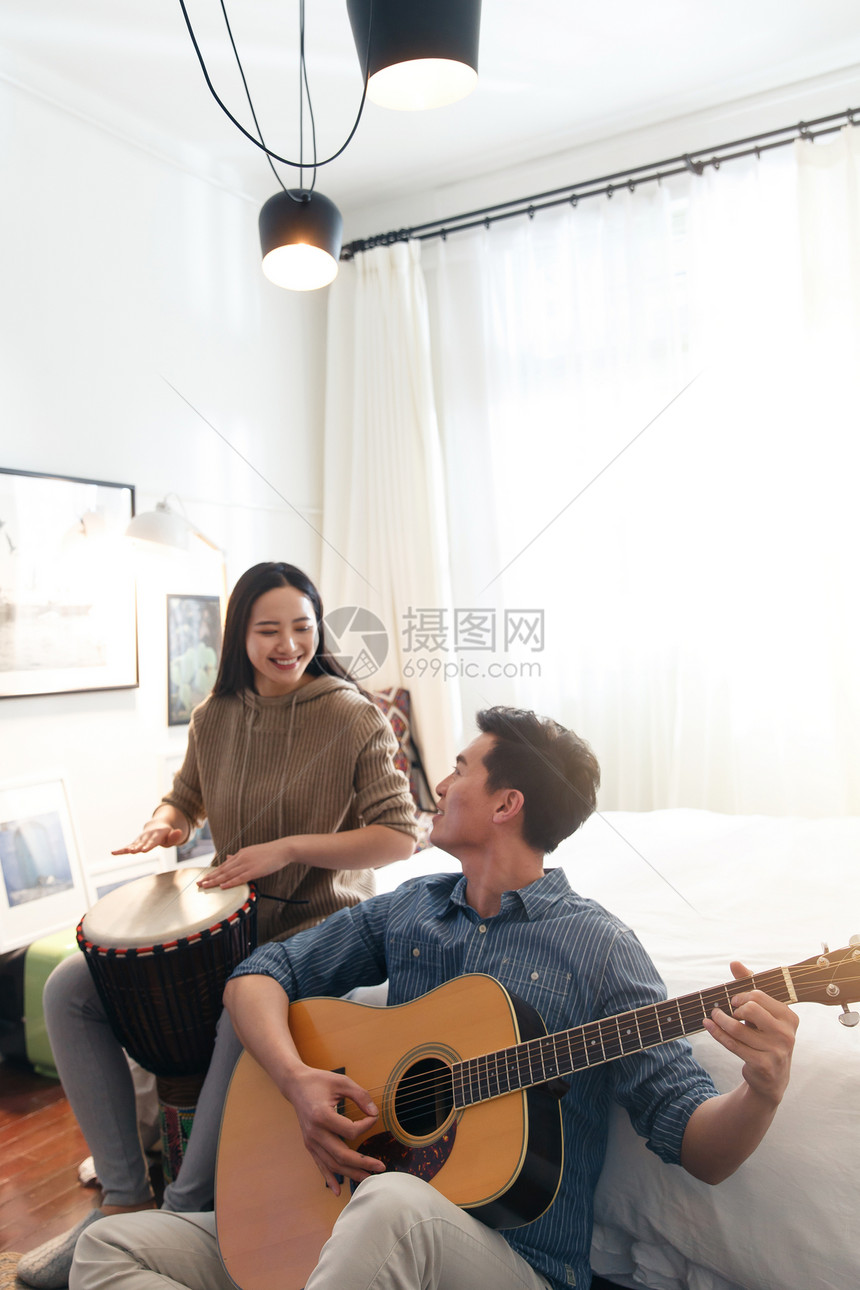 男朋友休闲装表现积极快乐情侣在家演奏乐器图片