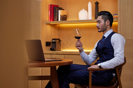 坐在餐桌前喝红酒的男性高清图片