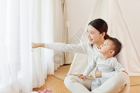 年轻宝妈陪宝宝看窗外风景关爱高清图片素材