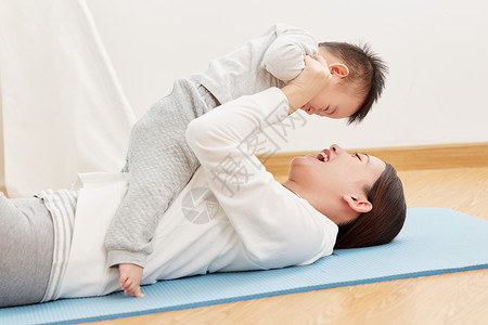瑜伽宝宝妈妈在瑜伽垫上和宝宝玩耍背景
