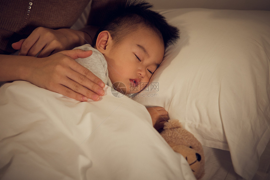 夜晚母亲轻抚熟睡的宝宝图片