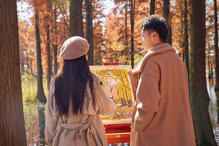 在画油画的女孩秋季情侣在树林里画油画背影背景