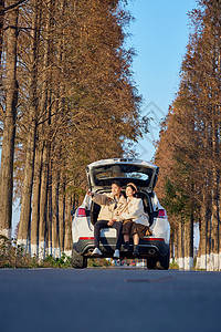 年轻情侣自驾出游坐在汽车后备箱拍照旅游高清图片素材
