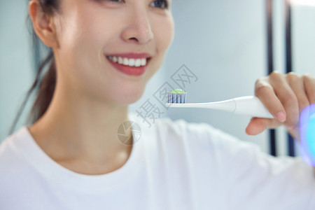 电动牙刷刷牙居家女性使用电动牙刷特写背景