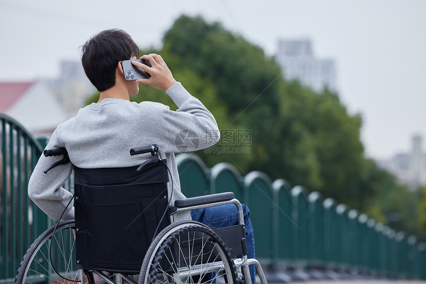 青年男性坐轮椅外出打电话背影图片