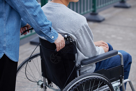 路人帮助坐轮椅的男性特写图片