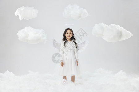 戴着天使翅膀的小女孩站在云多间图片