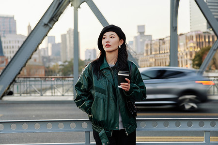 手捧咖啡站在桥上看风景的青年女性高清图片