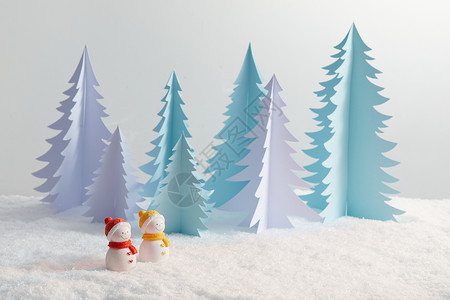 松树上的雪积雪上的一对小雪人背景