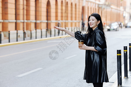 手拿咖啡的青年女性招手拦车高清图片