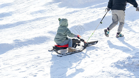 雪地里父亲拉着孩子滑雪橇背景图片