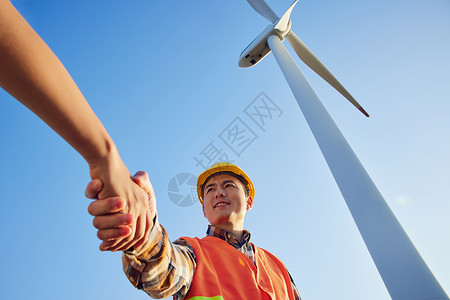 握手环保仰拍工程师在大风车下握手合作背景