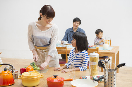 年轻妈妈在切菜和小女孩说话图片