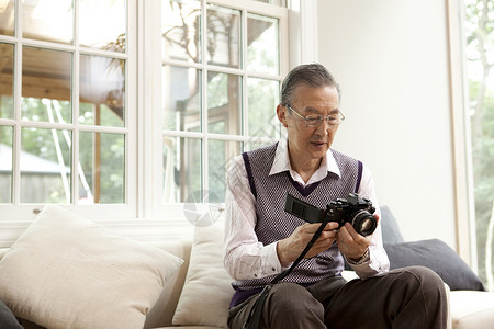 沙发上研究相机的老年人背景图片