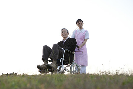 护工推着轮椅上的老年人户外散步图片