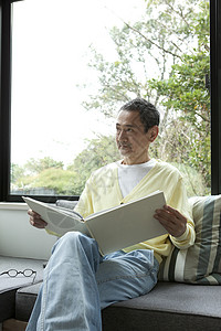 客厅窗前看书的中老年男性图片