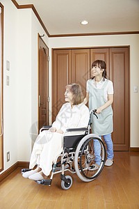 护工在室内推行坐在轮椅上的老人背景图片