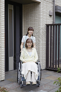 女性护工照顾轮椅上的老人出门散步图片