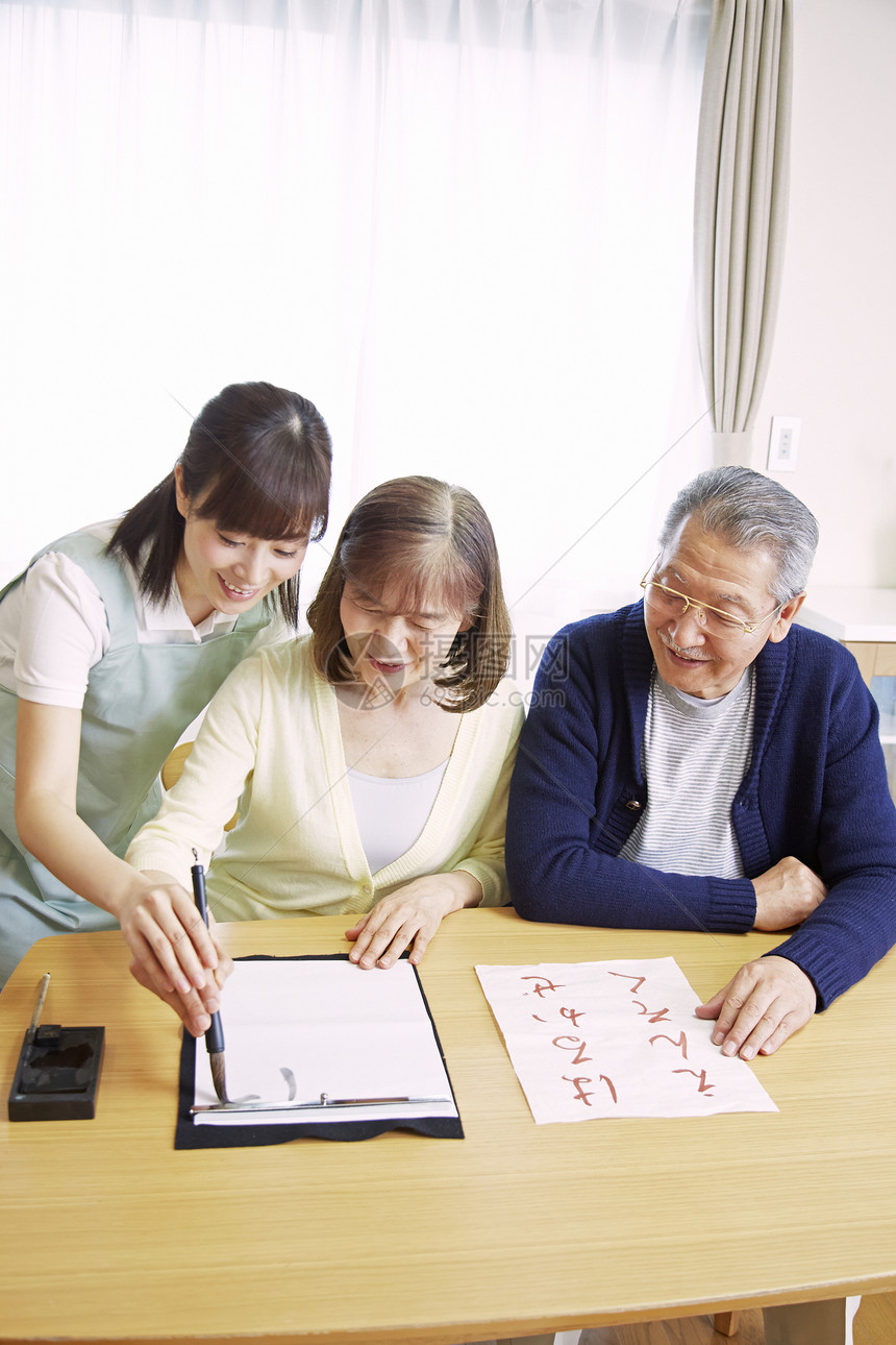 女性护工陪伴居家老人练习书法图片