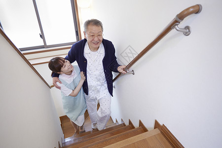 护工搀扶腿脚不便的老人上楼梯图片