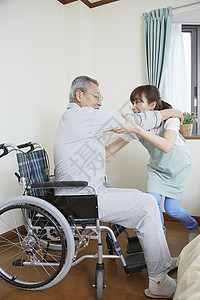 护工扶老人坐上轮椅图片