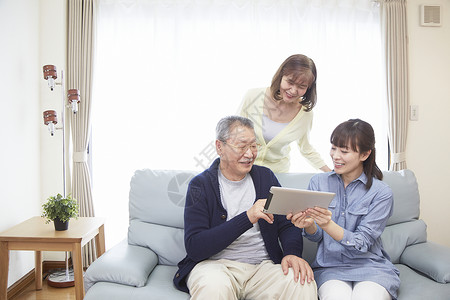 老年夫妇在和女儿在沙发上看平板电脑图片