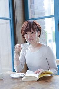 咖啡馆独自看书喝茶的年轻短发女性图片