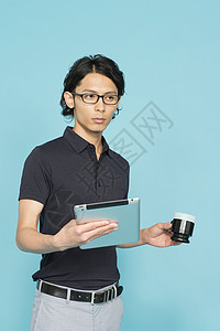 拿着平板电脑端着水杯的职场男士图片
