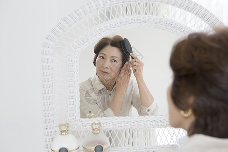 老年女性镜子前梳头发刷高清图片素材