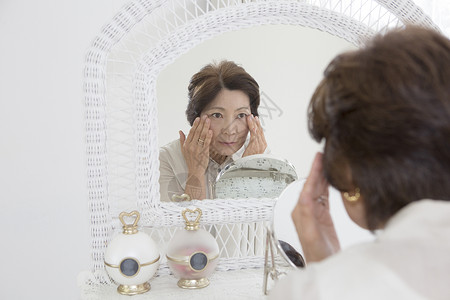 老年女性镜子前观察皮肤新鲜高清图片素材