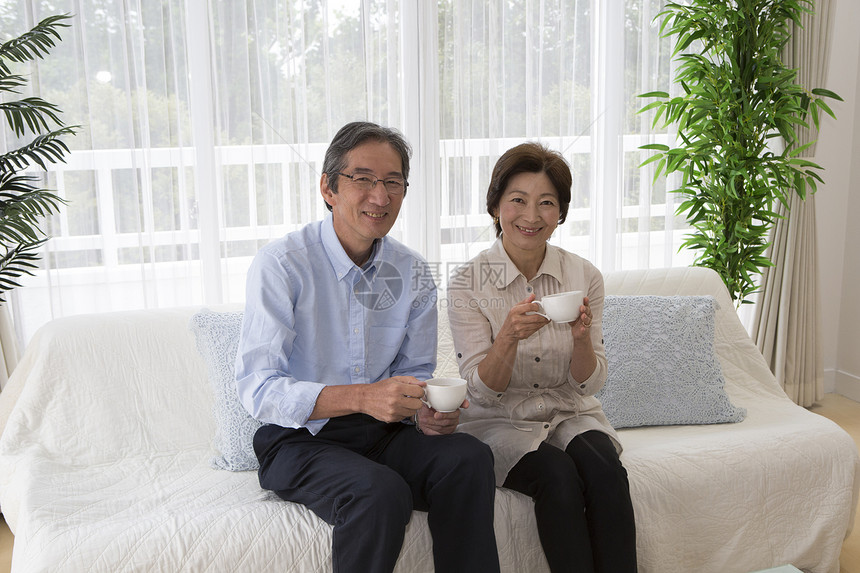 坐在沙发上喝下午茶的中年夫妇图片
