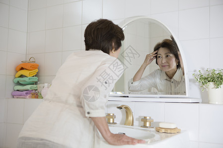 老年女性镜子前查看脸上的皱纹美人高清图片素材