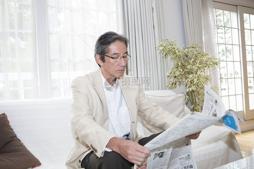 客厅沙发上的中老年男性看报纸图片