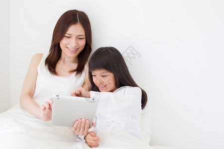妈妈跟女儿躺在床上看平板电脑图片
