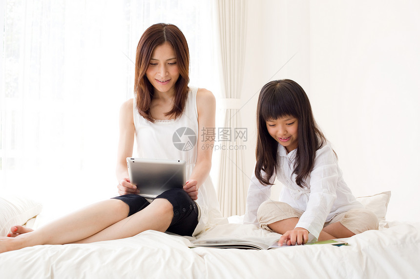 母亲跟女儿坐在床上看书图片