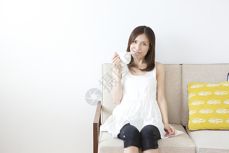 坐在沙发喝咖啡的女性图片