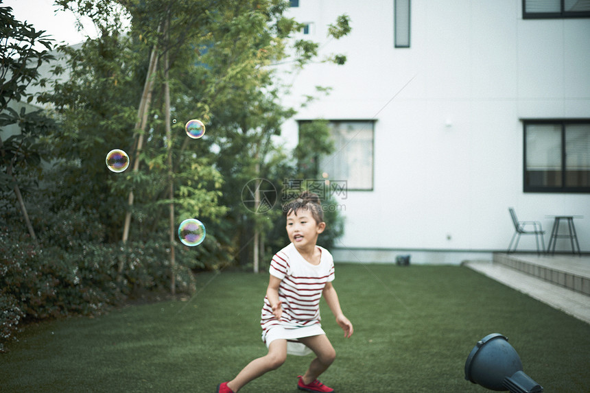 草坪上吹泡泡的小女孩图片