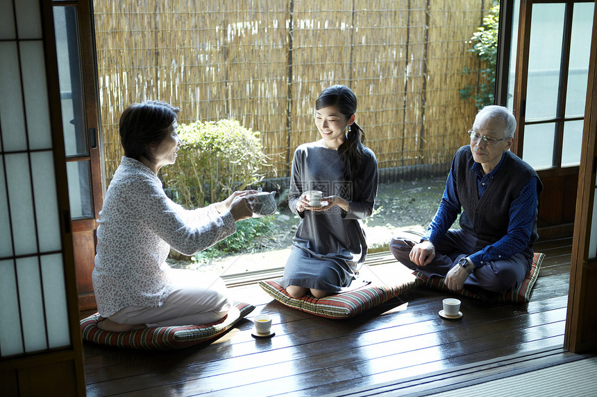 在庭院边喝茶聊天的老夫妇和女儿图片
