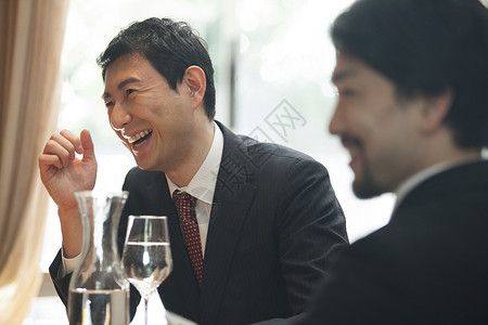 餐桌上开心聊天的商务男性图片
