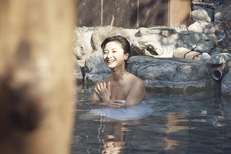 一个女人沉浸在干净舒适的温泉里微笑图片