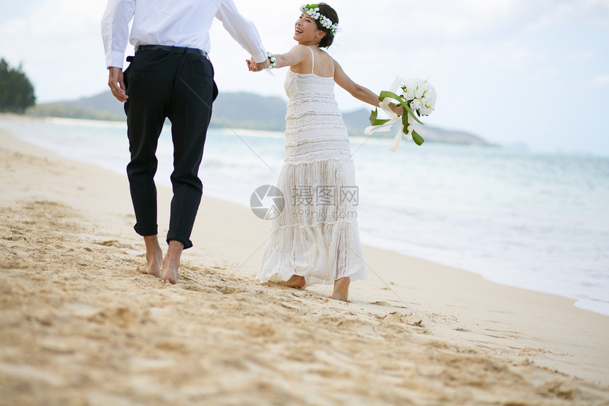 海滩边牵手的新婚夫妻图片