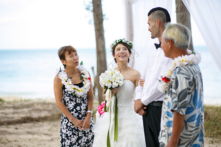 举办海滩婚礼的新婚夫妇和父母图片
