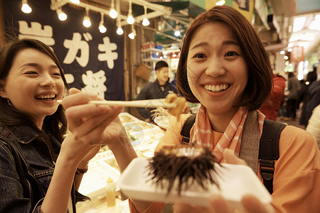 在日本旅行的女生在市集微笑吃东西背景图片