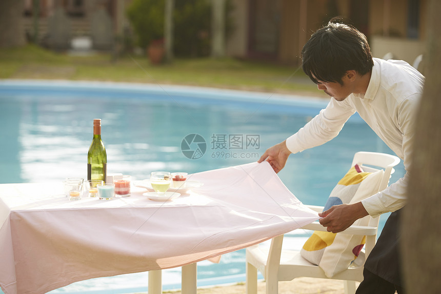 酒店员工在收拾泳池边的餐桌图片