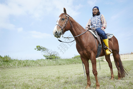 在牧场骑马的男子图片
