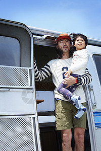 在露营车门口抱着儿子的男人图片