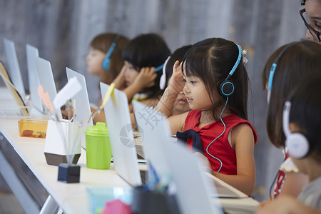 带着耳机在电脑前学习的幼儿园学生参加考试高清图片素材